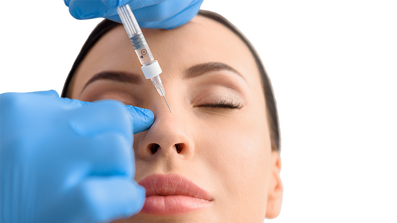 Eine junge Frau bekommt eine Injektion in die Nase